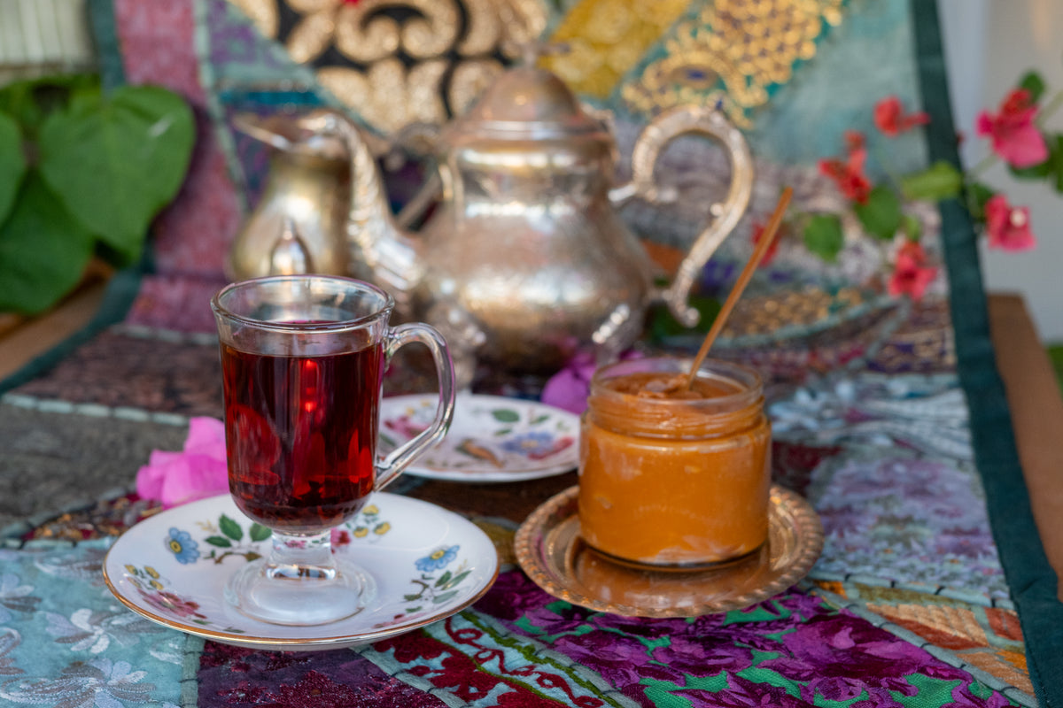 Tea served from a silver pot on a patterned cloth
